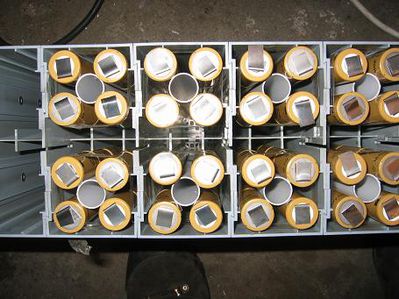 Stränge im Gehäuse
Die unterseitig fertig verbundenen Stränge mit Mittelrohr als Abstandshalter im Batteriegehäuse. Man sieht sehr schön die luftige Lagerung. Das Rohr ist unterseitig verschlossen damit die gesamte Ventilationsluft an den Zellen vorbeiströmt. Die gemessene Druckdifferenz im Luftstrom ist wesentich geringer als vorher, der Massendurchsatz liegt mindestens um den Faktor zwei Höher. Dafür ist der Innenwiederstand der Zellen aber auch drei mal so hoch wie der der Original verwendeten Sanyos.
